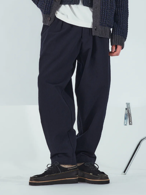 UNIVERSAL WORKS PLEATED TRACK PANT IN NAVY CORD