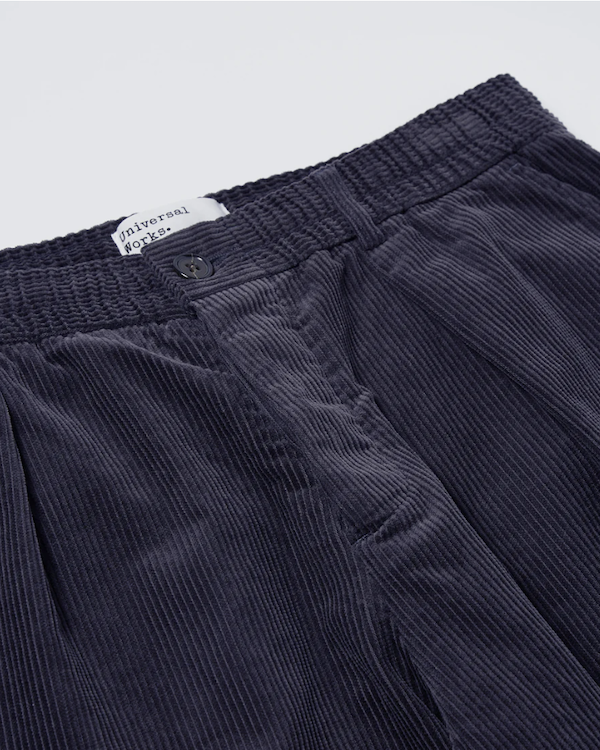 UNIVERSAL WORKS PLEATED TRACK PANT IN NAVY CORD