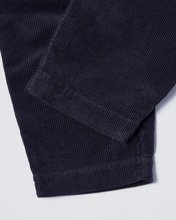 UNIVERSAL WORKS PLEATED TRACK PANT IN NAVY CORD